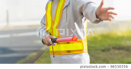 A man in work clothes directing traffic 96530356