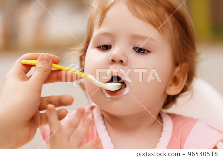feeds baby with a spoon porridge. A little girl 96530518