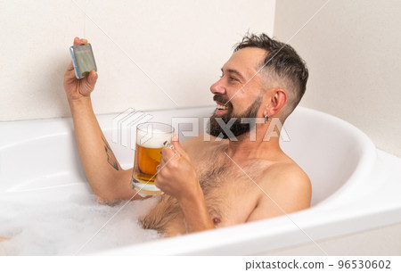 Bearded man watching football with beer in bath Bearded man watching football with beer in bath 96530602