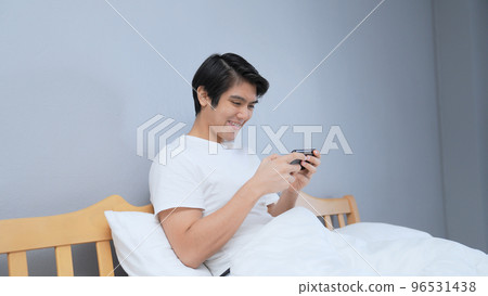Holiday concept of 4k Resolution. Asian man playing mobile game in bedroom. online game fun. 96531438