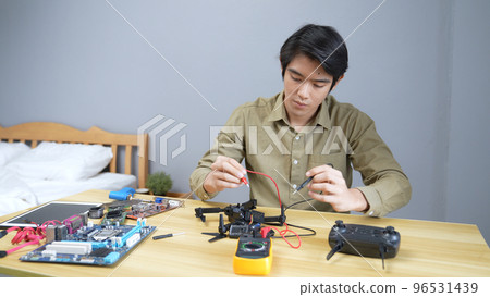 technology concept of 4k Resolution. Asian man fixing drone in room. check for damage. 96531439