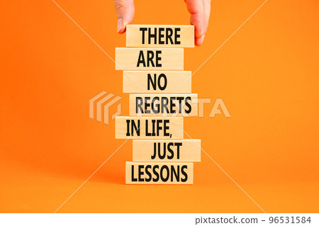 Regrets or lessons symbol. Concept words There are no regrets in life just lessons on wooden blocks on a beautiful orange background. Businessman hand. Business regrets or lessons concept. Copy space 96531584