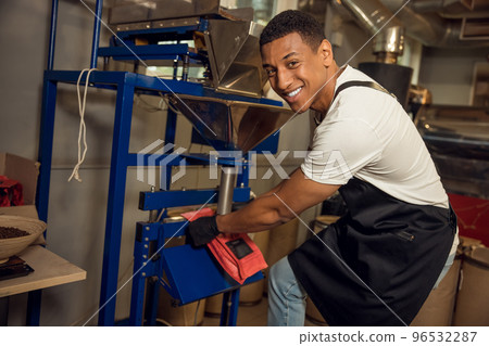 Cheerful worker sealing a coffee bag with the heat sealer 96532287