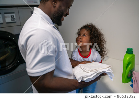 Joyful young father and his daughter at the laundromat 96532352