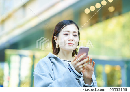 A woman watching a screen of a smartphone A woman watching a screen of a smartphone 96533166