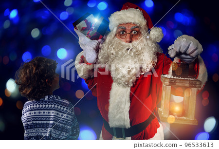 Santa claus is giving a present for christmas to a little boy 96533613