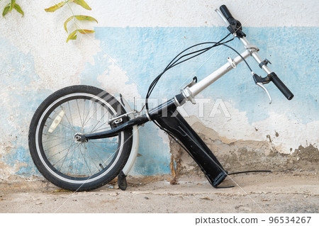 Front half of a bicycle broken into two parts against the wall 96534267