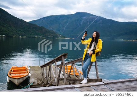 The girl tourist in a yellow jacket. Active woman relaxing in the Norway. Travelling, lifestyle, adventure. The girl tourist in a yellow jacket. Active woman relaxing in the Norway. Travelling, lifestyle, adventure. 96534603