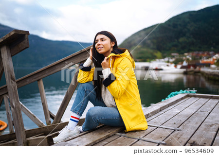 The girl tourist in a yellow jacket. Active woman relaxing in the Norway. Travelling, lifestyle, adventure. The girl tourist in a yellow jacket. Active woman relaxing in the Norway. Travelling, lifestyle, adventure. 96534609