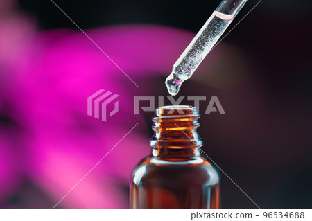 Closeup dropper with legalized CBD oil at the tip, near to the CBD oil container 96534688