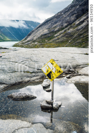 Yellow warning sign about the collapse in the mountains. Landslides and falling rocks. 96534950