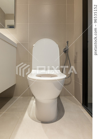 Front view of white toilet bowl with opened lid in a modern bathroom. Sanitary equipment for a home Front view of white toilet bowl with opened lid in a modern bathroom. Sanitary equipment for a home 96535152