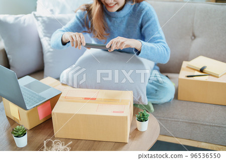 Starting small business entrepreneur of independent Asian woman smiling using computer laptop with cheerful success of online marketing package box items and SME delivery concept. 96536550