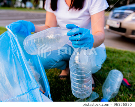 close-up of a hand in a rubber glove collects a plastic garbage bag. Cleaning the area from household waste. Environment ecology concept 96536850