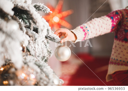 Happy girl decorating a beautiful Christmas tree Happy girl decorating a beautiful Christmas tree 96536933