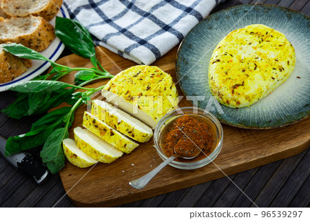 Sliced fried cottage cheese with cumin and turmeric on wooden board 96539297