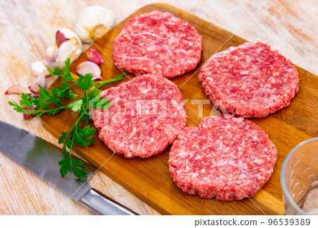 Raw handmade minced pork burgers patties on board Raw handmade minced pork burgers patties on board 96539389