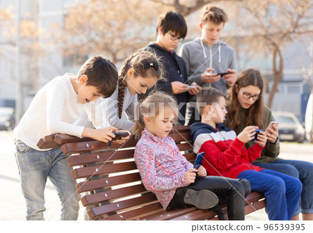 Children addicted in their phones outdoors Children addicted in their phones outdoors 96539395