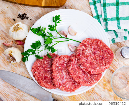 Billets for burgers from fresh minced meat with spices on wooden board Billets for burgers from fresh minced meat with spices on wooden board 96539412