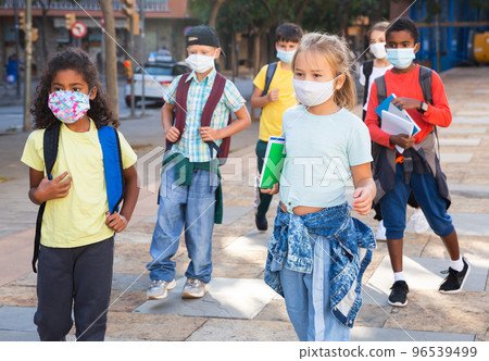Tweenagers in medical masks walking outside school building Tweenagers in medical masks walking outside school building 96539499