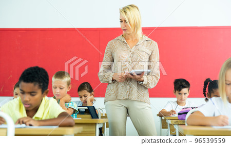 Female teacher working with tweenager pupils in classroom 96539559
