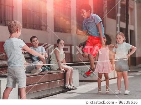 Mexican boy playing rubber band jumping game with friends 96539616