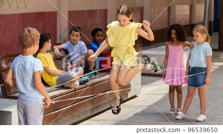 Happy smiling little friends playing with chinese jumping rope Happy smiling little friends playing with chinese jumping rope 96539650