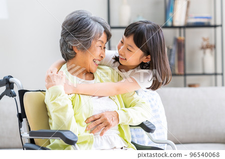 Wheelchair grandmother and elementary school granddaughter in the living room Wheelchair grandmother and elementary school granddaughter in the living room 96540068