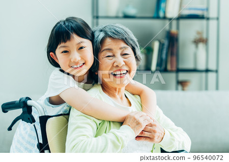 Wheelchair grandmother and elementary school granddaughter in the living room Wheelchair grandmother and elementary school granddaughter in the living room 96540072