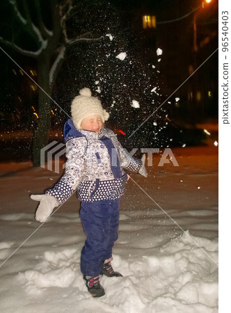 happy little girl standing on city street in winter evening. happy little girl standing on city street in winter evening. 96540403