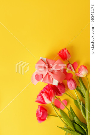 Beautiful spring surprise on Mothers or Womans International day 8 march, Wedding, Saint Valentine. Bouquet of pink tulips, gift box on yellow table. Flat lay, stylish banner for site, seasonal flyer 96541178