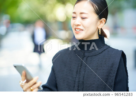 A woman watching a screen of a smartphone 96541283