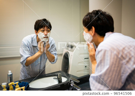 A man applying shaving foam to his face A man applying shaving foam to his face 96541506