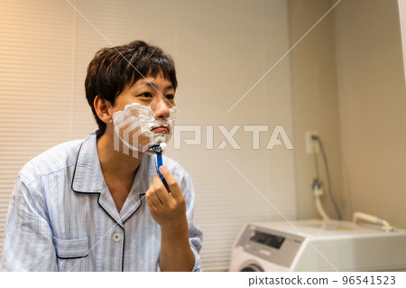 A man in his 40s shaving with a T-shaped razor 96541523