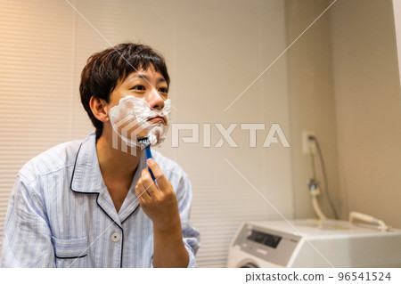 A man in his 40s shaving with a T-shaped razor A man in his 40s shaving with a T-shaped razor 96541524