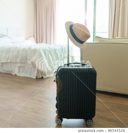 Black Luggage with hat in modern hotel room after door opening. Baggage for Time to travel, service, journey, trip, summer holiday and vacation concepts 96543520
