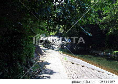 Riverside promenade with waterfall view 96544567