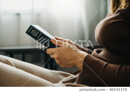 Hands together in prayer to God along with the bible In the Christian concept and religion, woman pray in the Bible 96545378