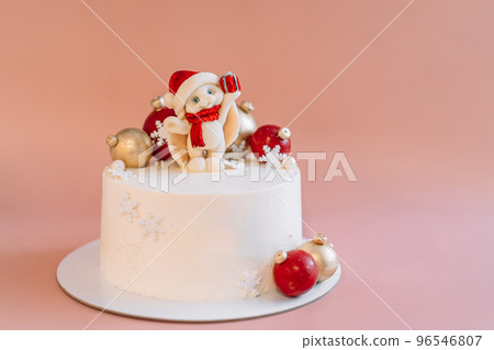 White Christmas cake with caramel bunny and balls against pink background 96546807