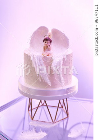 A figurine of a little angel with wings sits on a white cake 96547111