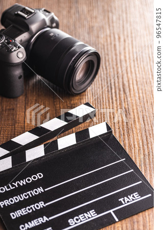 Black clapper board and digital camera on wooden table. 96547815