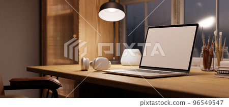 Cozy Scandinavian home workspace with laptop mockup, light from table lamp on wood table. Cozy Scandinavian home workspace with laptop mockup, light from table lamp on wood table. 96549547