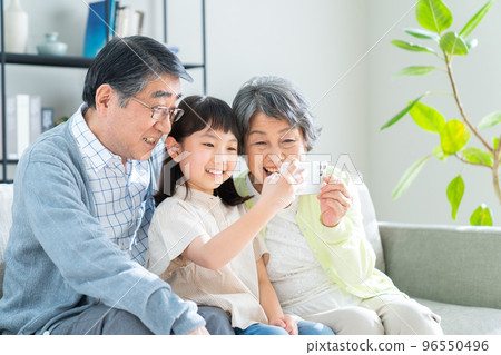 Granddaughter and senior couple looking at smartphone 96550496