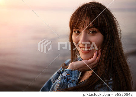 Portrait of a young woman on the background of the sea at sunset 96550842