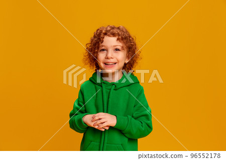 Portrait of cute little girl, child with curly red hair posing, smiling isolated over yellow background 96552178