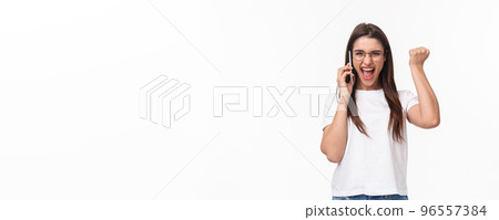 Communication, technology and lifestyle concept. Portrait of successful happy and excited woman winning, receive great news on phone, fist pump triumphing and saying yes, hold smartphone near ear 96557384