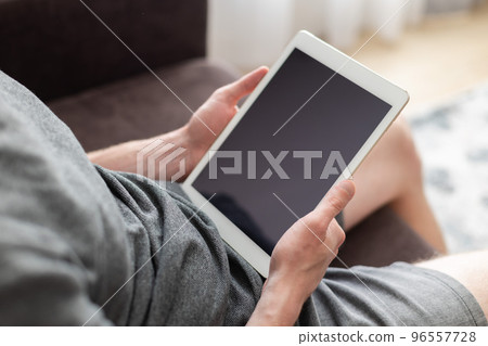 Man sitting on a couch with a tablet in his hands. Mockup. Man sitting on a couch with a tablet in his hands. Mockup. 96557728