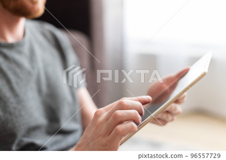 Man choose something on a tablet with his point finger. Using technology. Man choose something on a tablet with his point finger. Using technology. 96557729