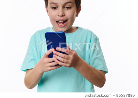 Selective focus on mobile phone in the hands of a teenager boy, expressing surprise while using smartphone, browsing websites, scrolling news feed, checking social media content, isolated on white Selective focus on mobile phone in the hands of a teenager boy, expressing surprise while using smartphone, browsing websites, scrolling news feed, checking social media content, isolated on white 96557880