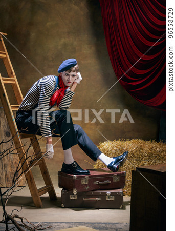 Portrait of male mime artist expressing sadness and loneliness over dark retro circus backstage background. Concept of human emotions, art, fashion, style 96558729